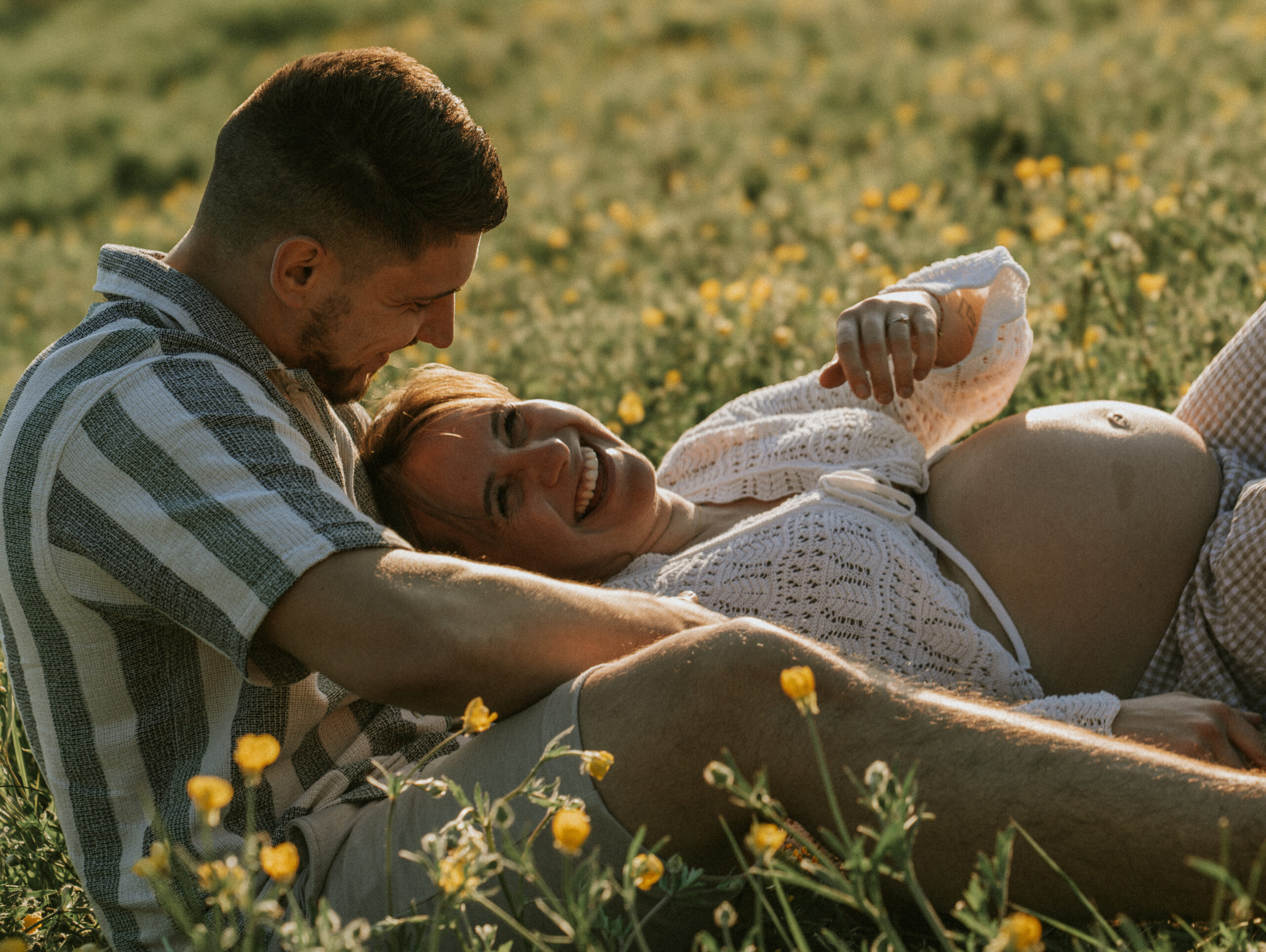 Couple riant dans un champ au coucher du soleil