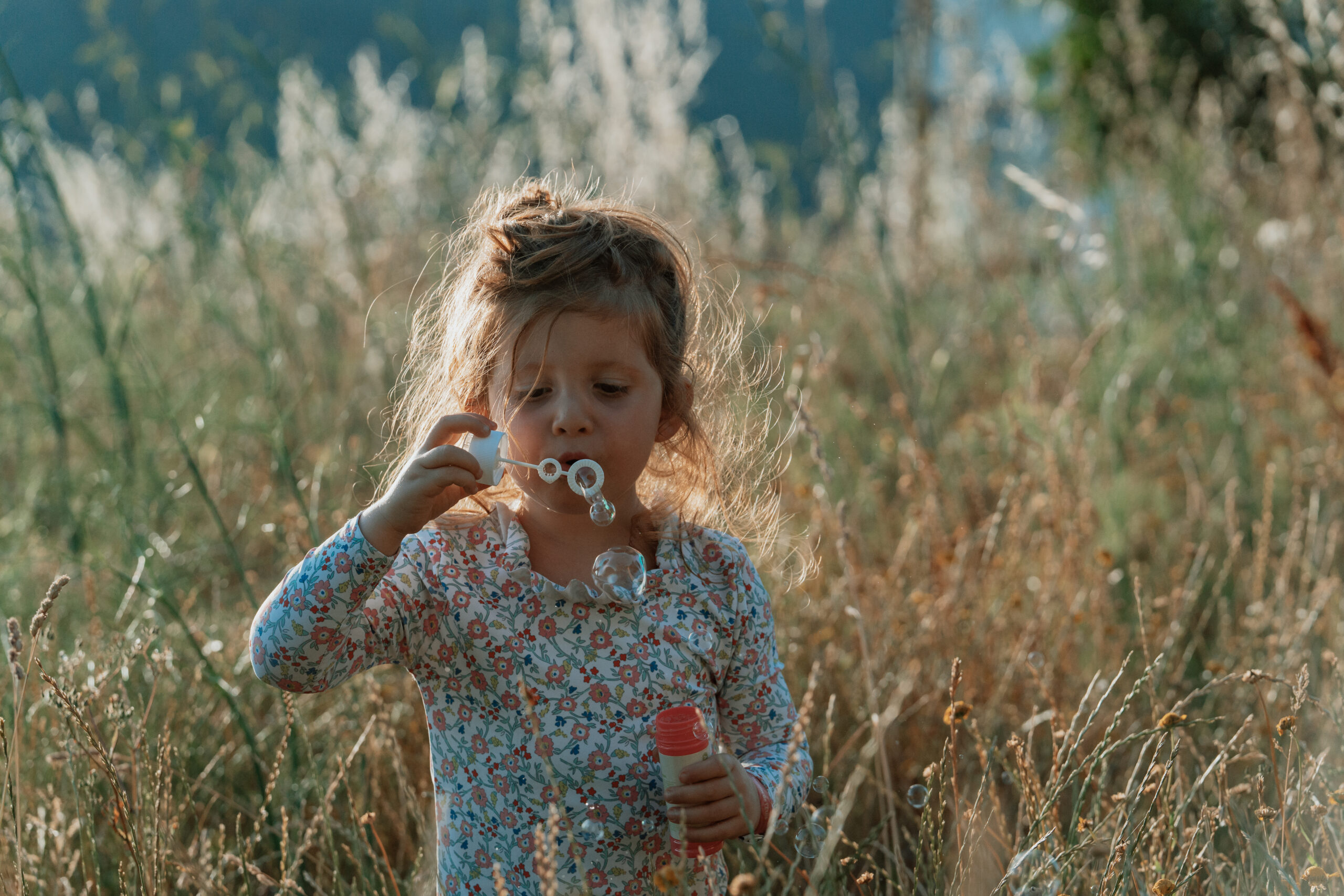 Enfant jouant avec des bulles dans les herbes hautes